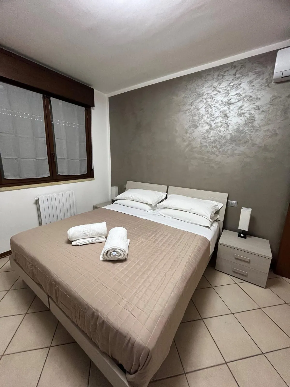 Camera matrimoniale con letto, comodini e parete decorata